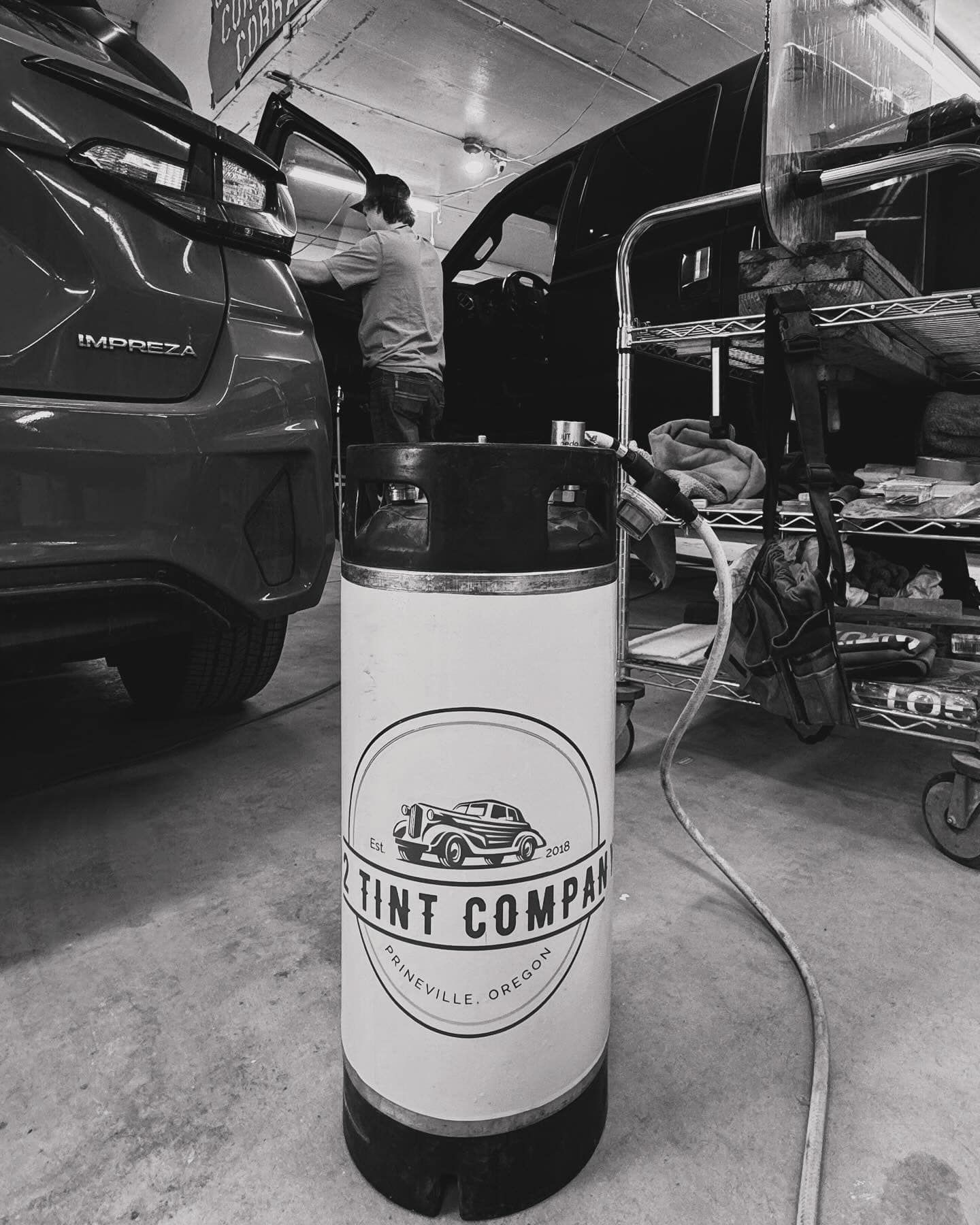 A black and white photo of a tint company bottle in a garage.