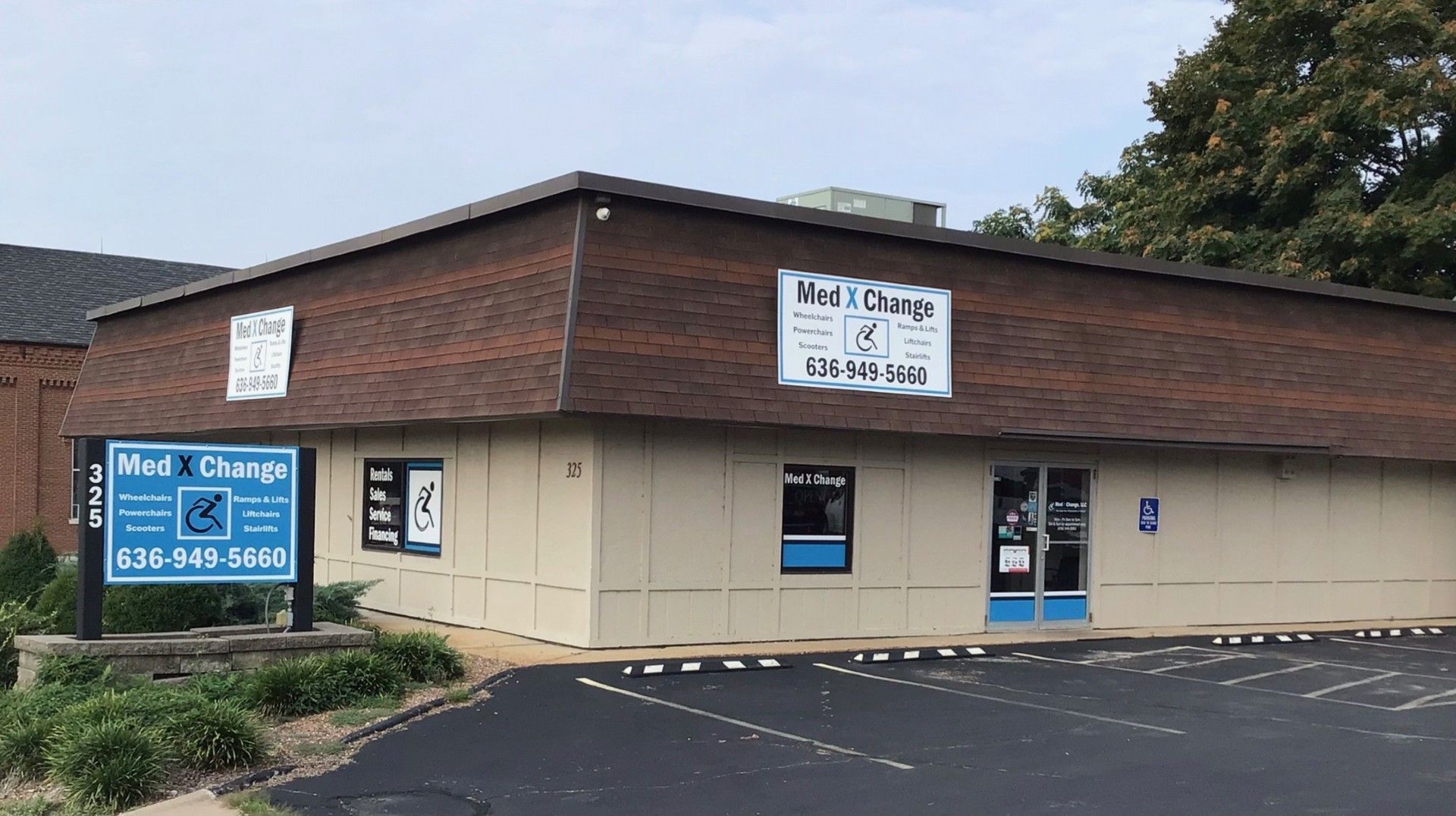 Single-story beige and brown commercial building with “Med X Change” signs and parking lot outside