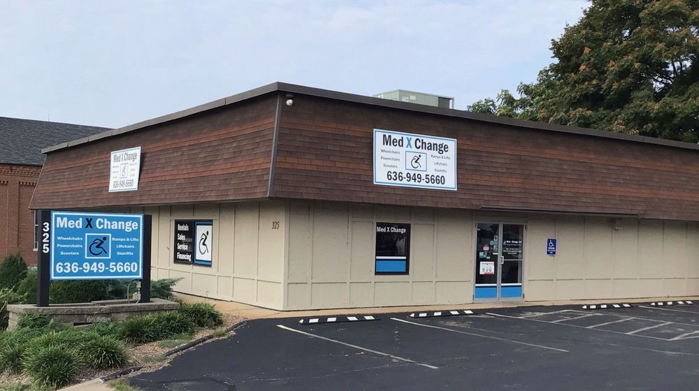Single-story beige and brown commercial building with “Med X Change” signs and parking lot outside