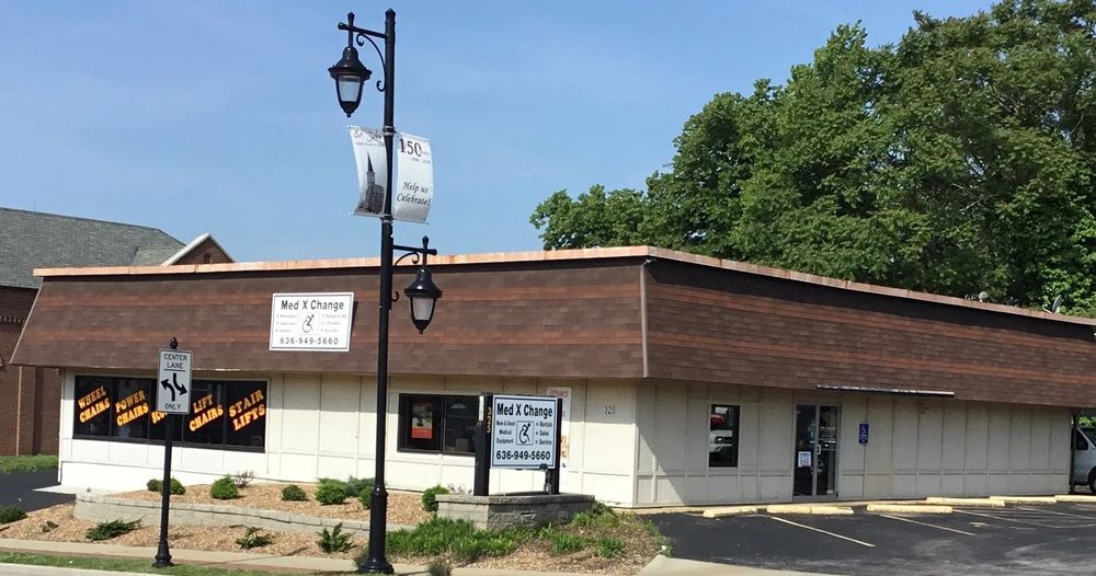 Person assisting wheelchair user up a ramp into a van.