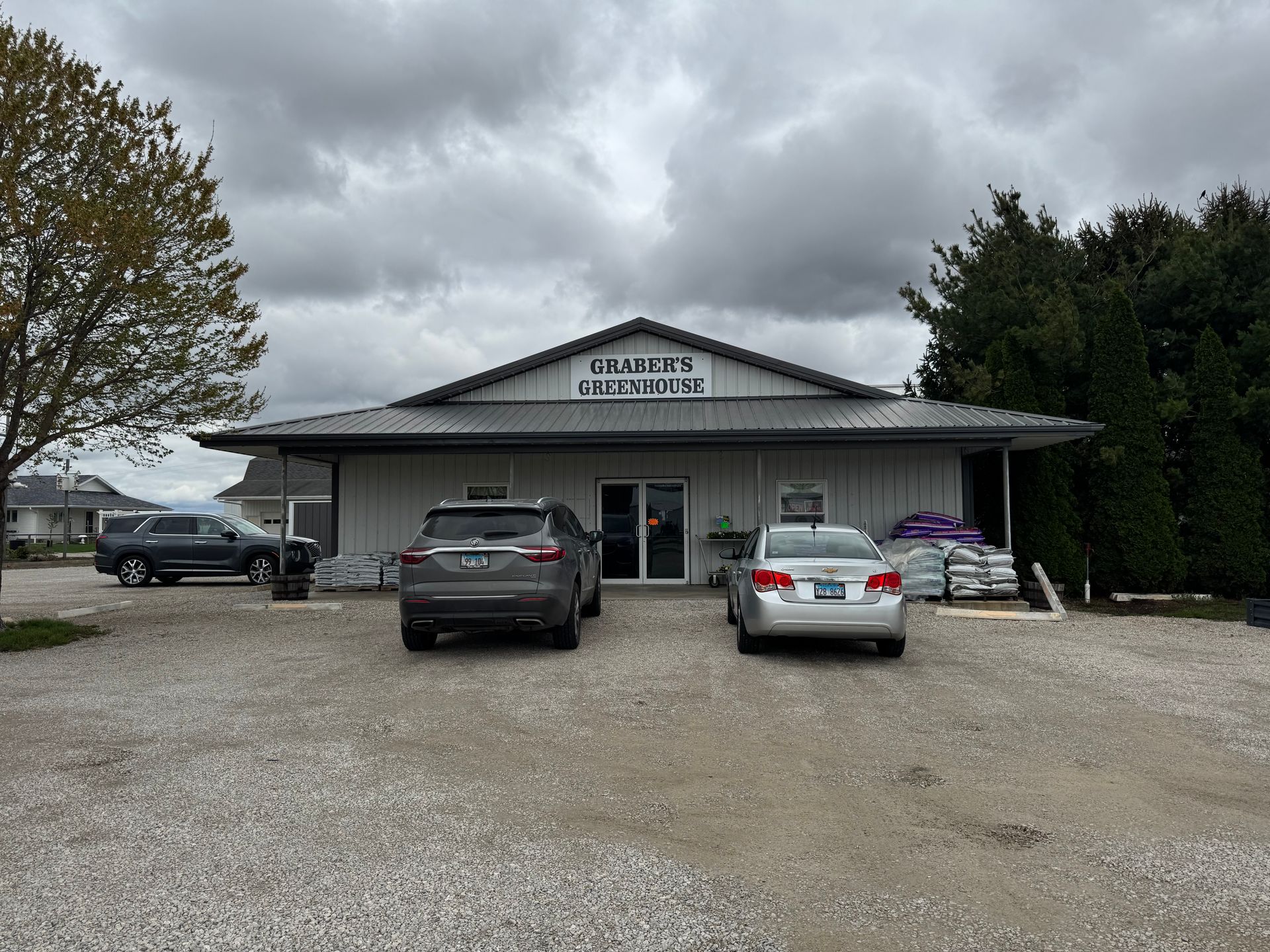 Two cars are parked in front of a building on a cloudy day.