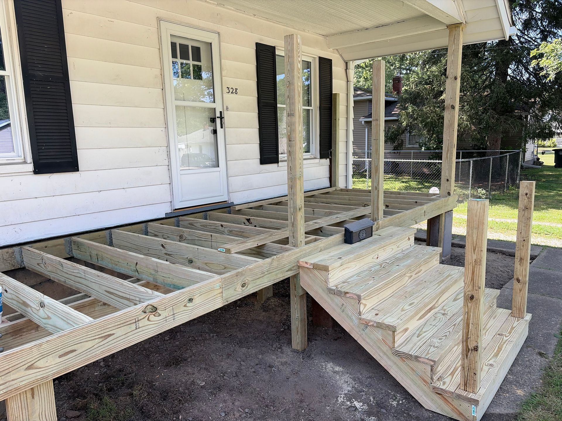 Wooden porch ramp and stairs under construction beside a white house