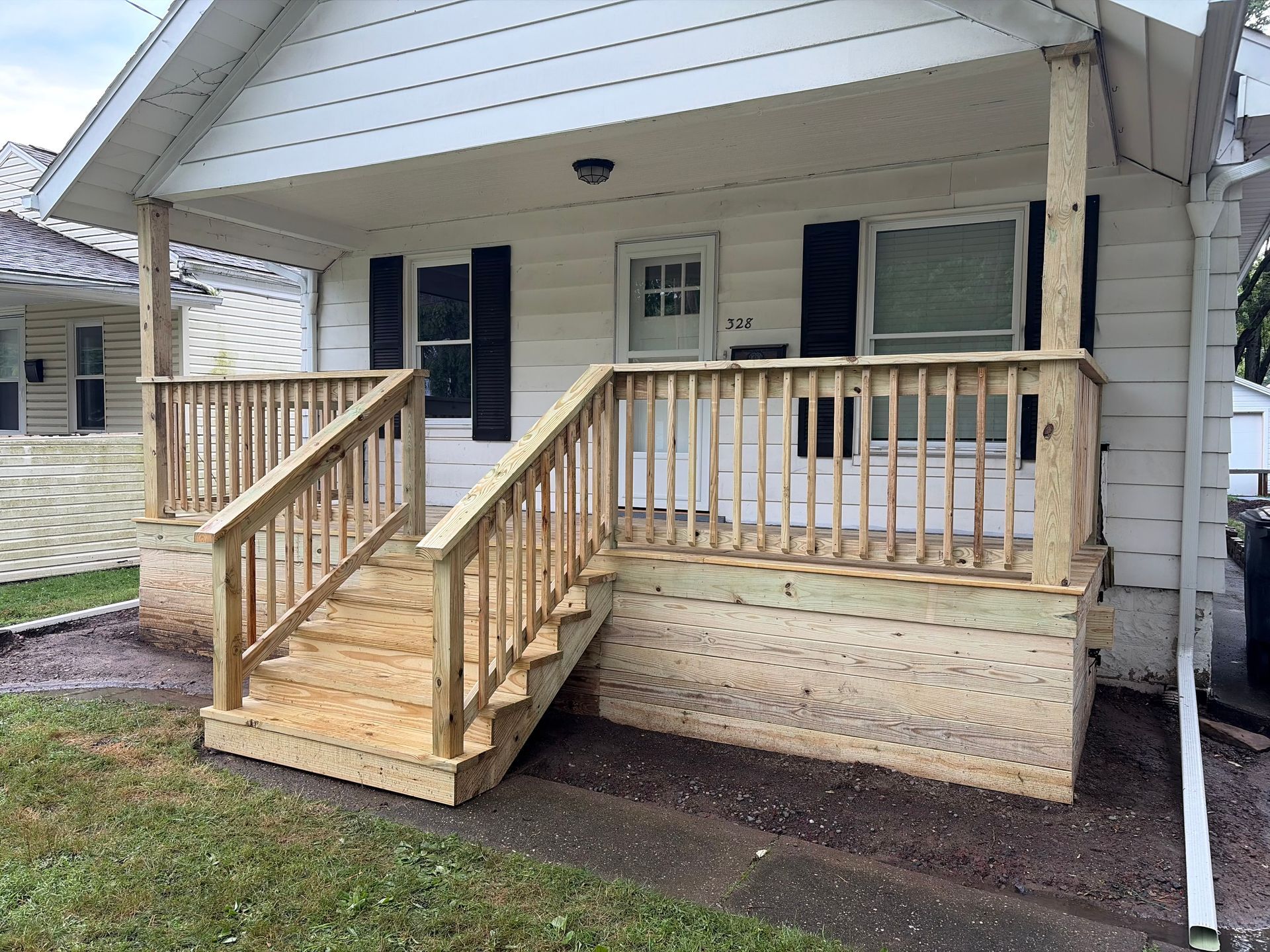 Front porch with wooden steps and railing on a white house with blue shutters