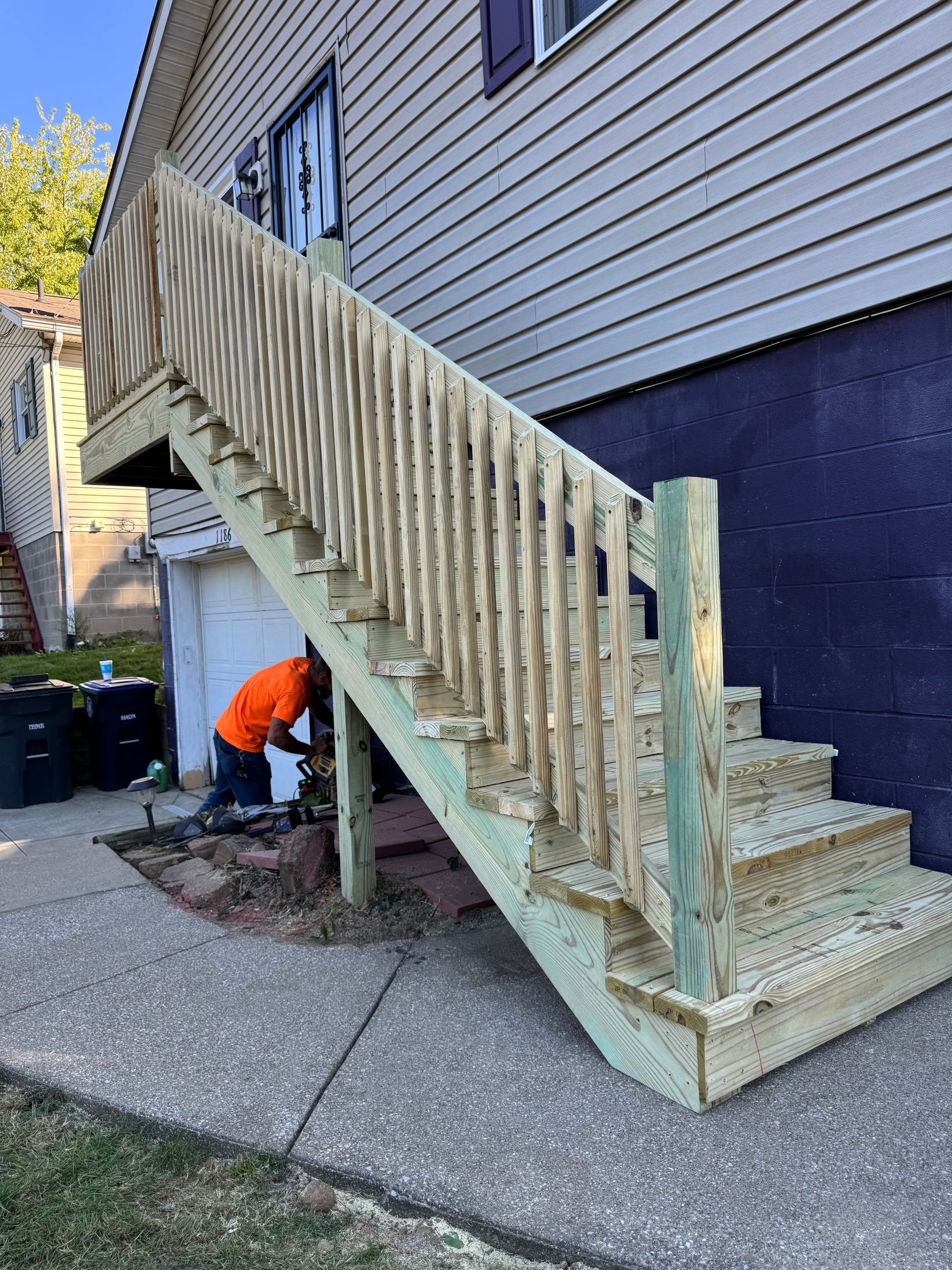 Newly built wooden exterior staircase with a person working at its base.