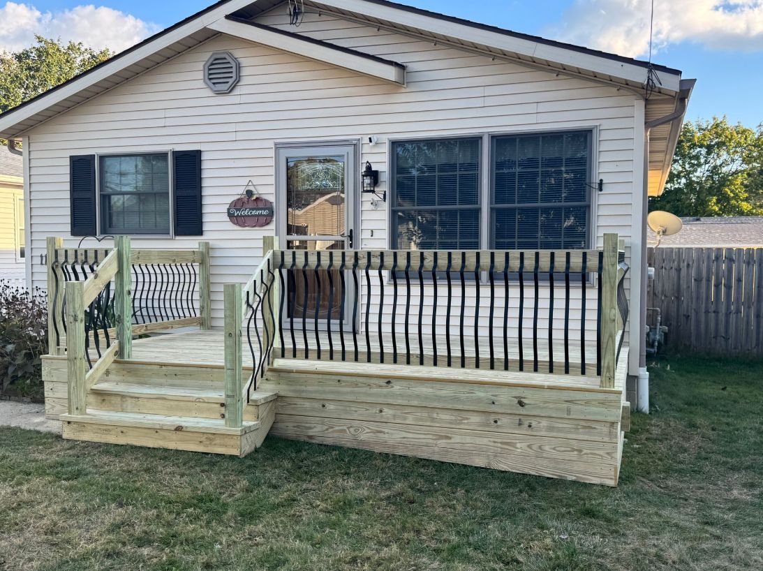 Cottage with new wooden deck and steps; black wavy railing.