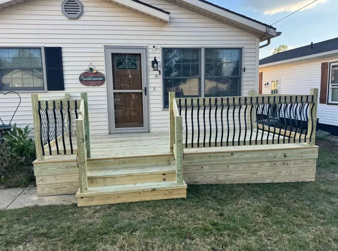 Wooden deck and steps leading to a house entrance with ornate railings.