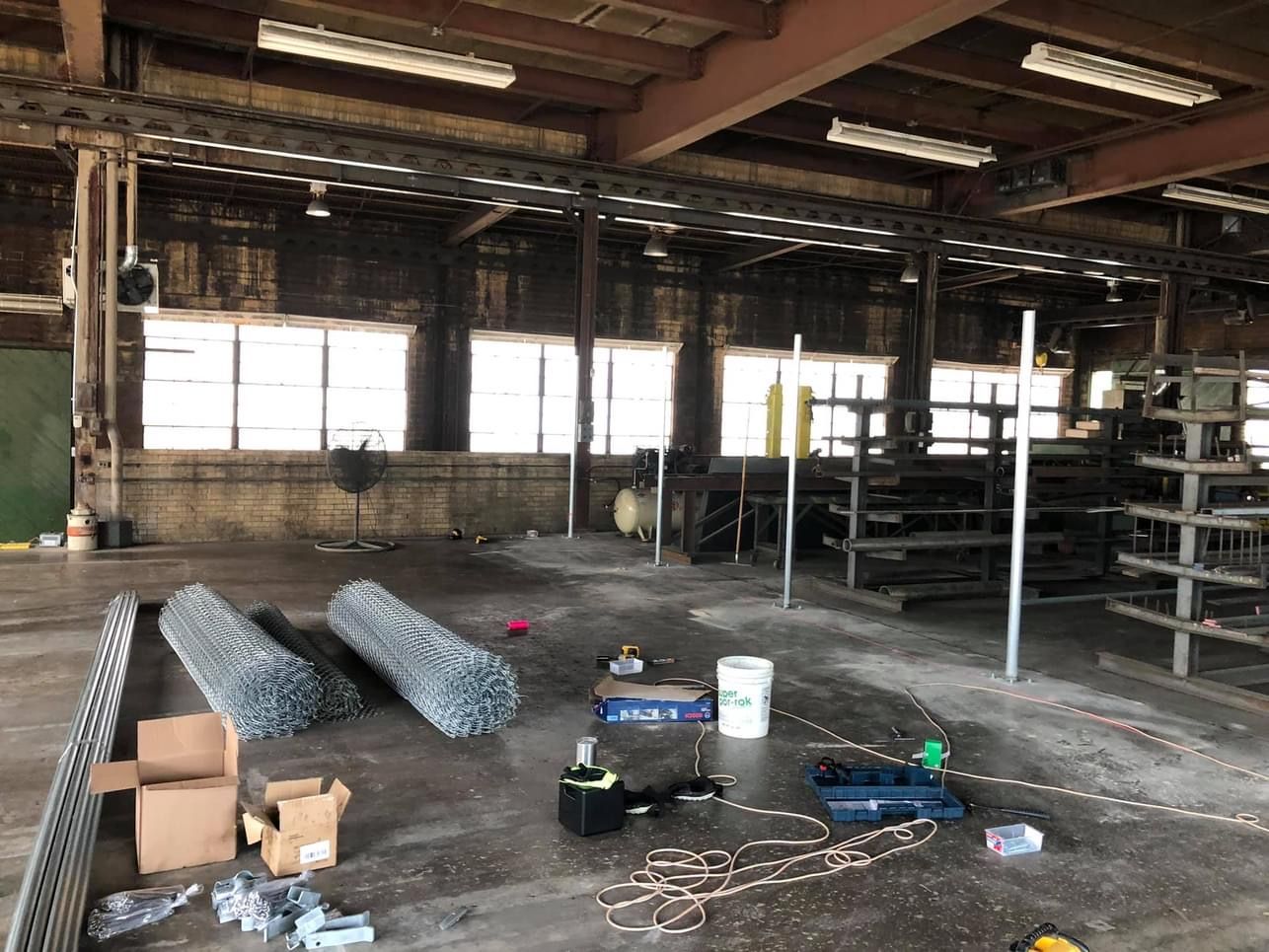 Interior of a warehouse with windows, tools, and metal shelving.