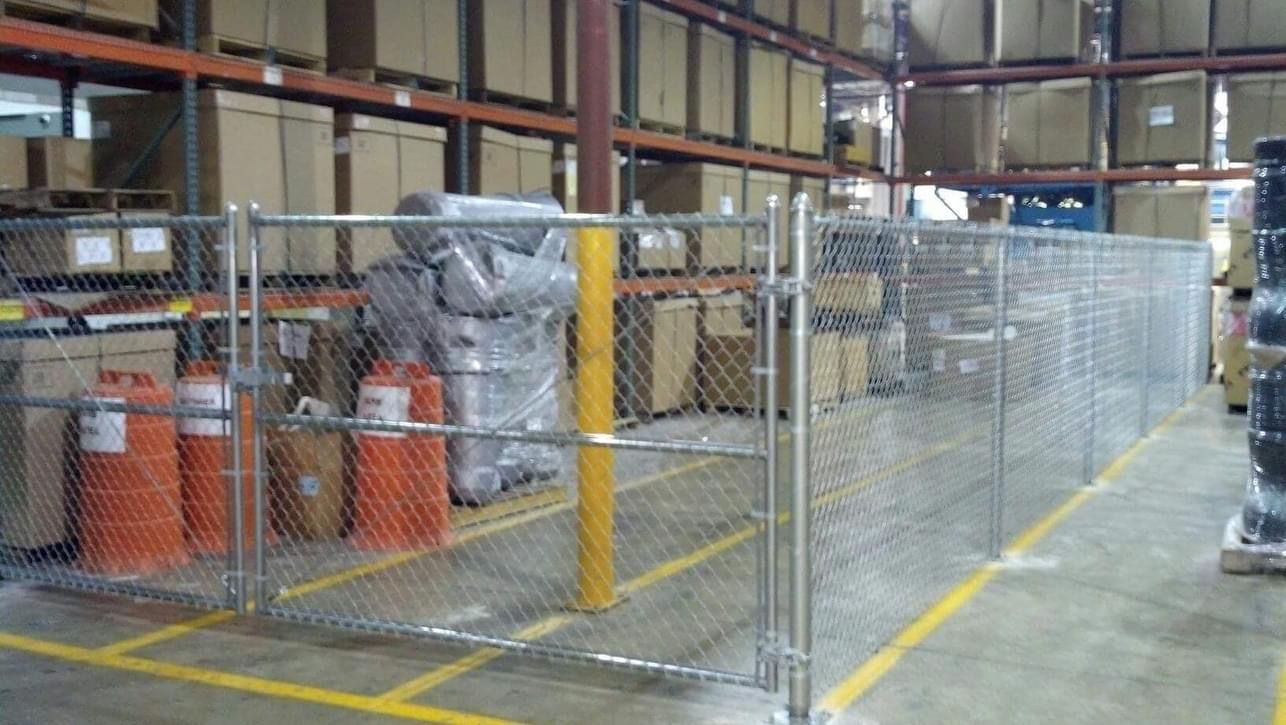 Warehouse interior with a chain-link fenced-in area containing fire extinguishers and wrapped items.