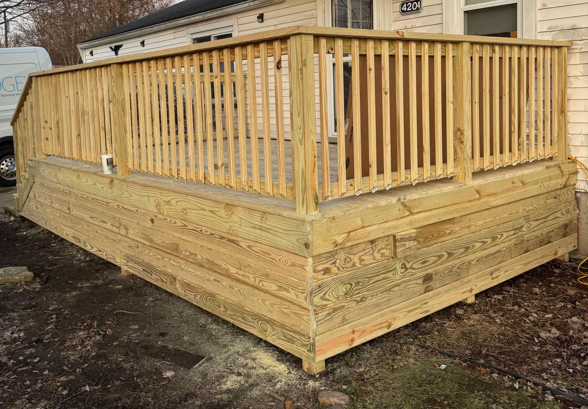 Wooden deck with railing attached to a house.