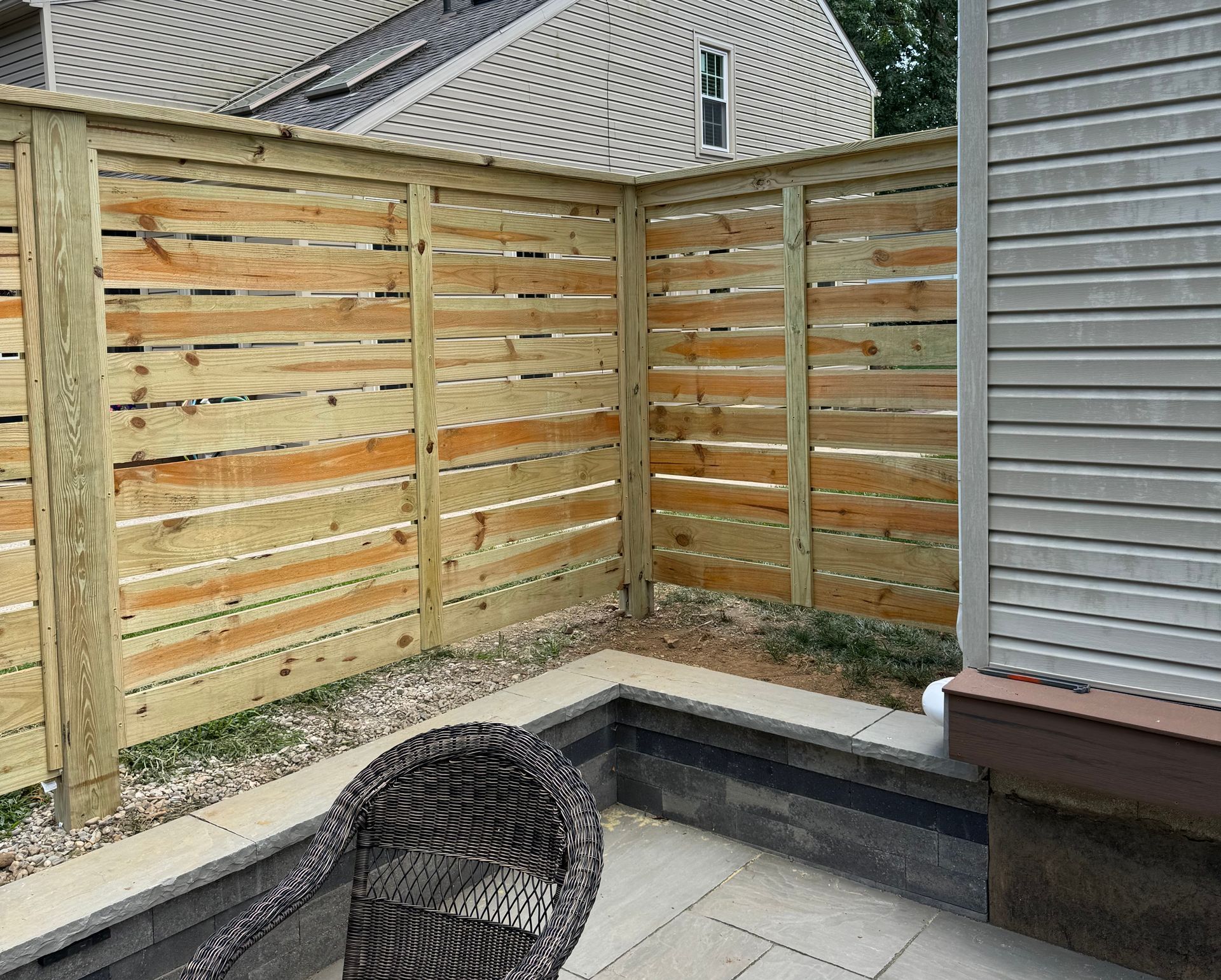 Wooden fence and patio corner with a wicker chair.