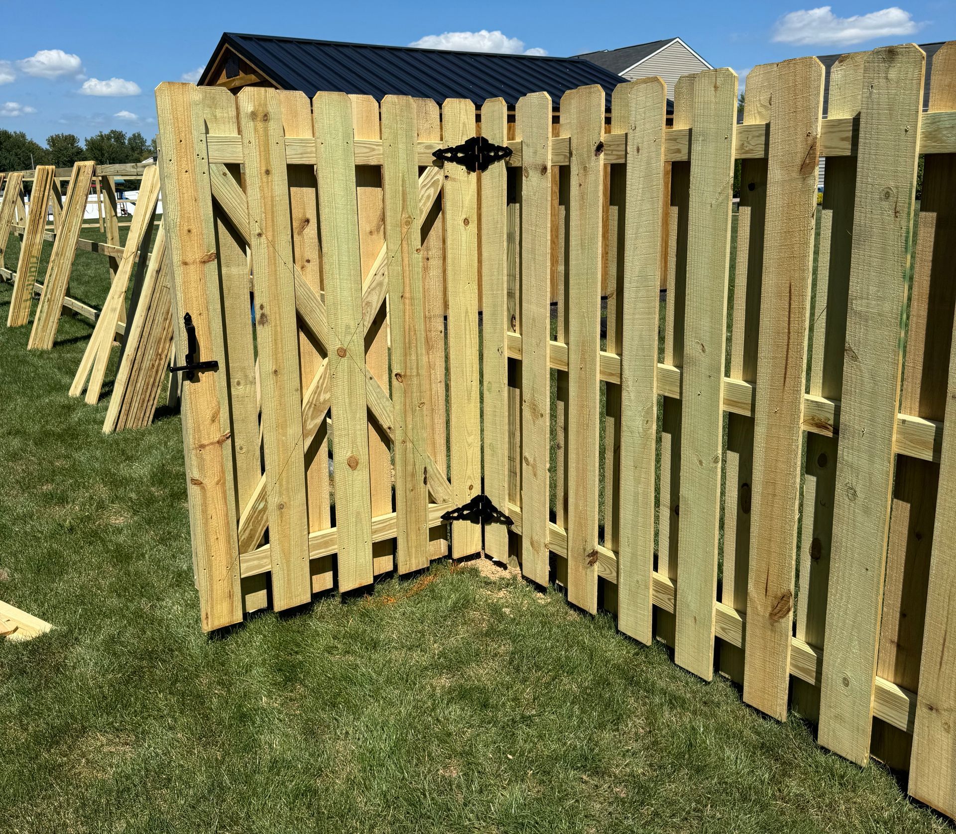 Wooden fence with a gate in a grassy yard.