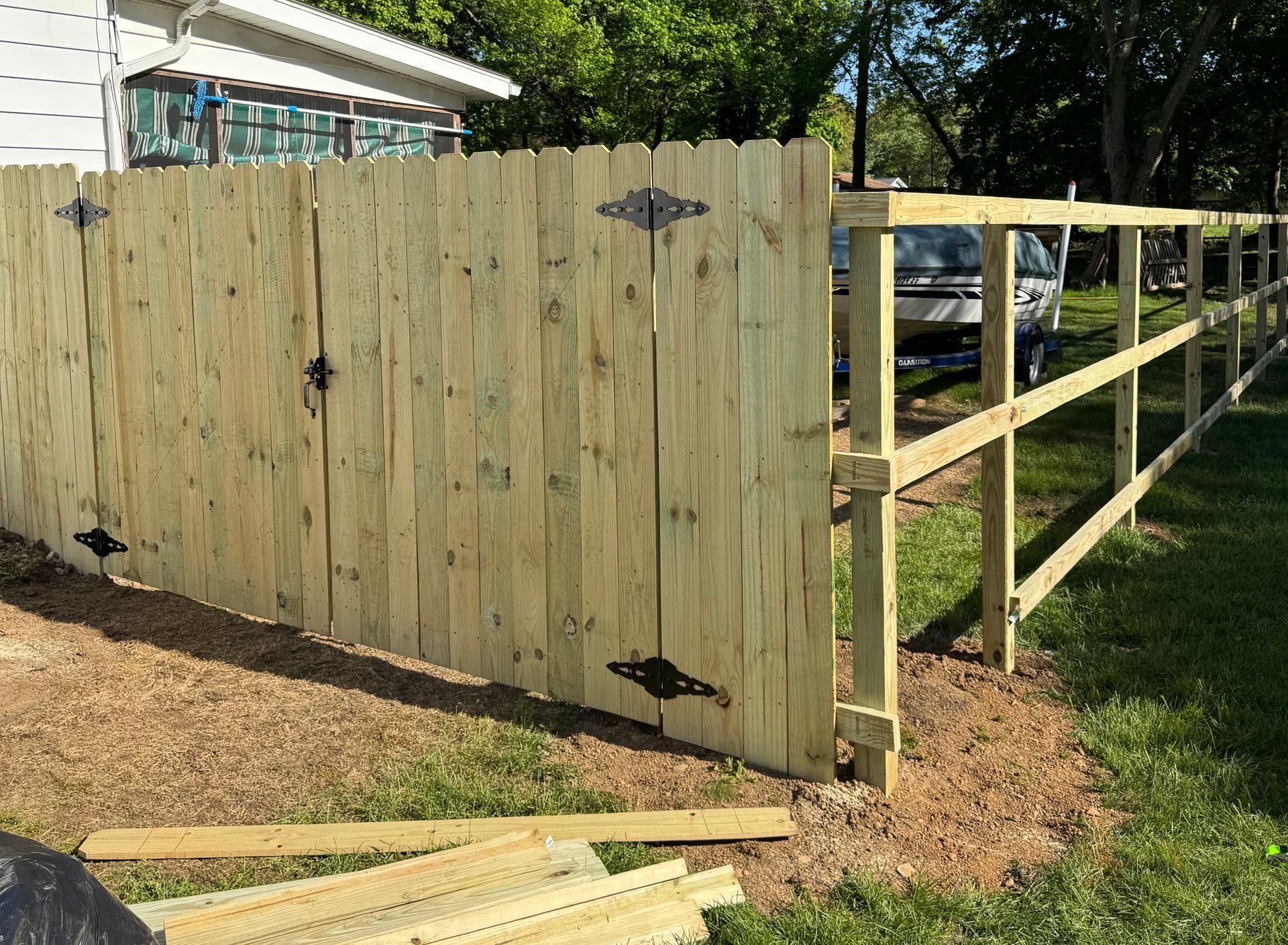Wooden fence with a gate, built on a grassy edge.