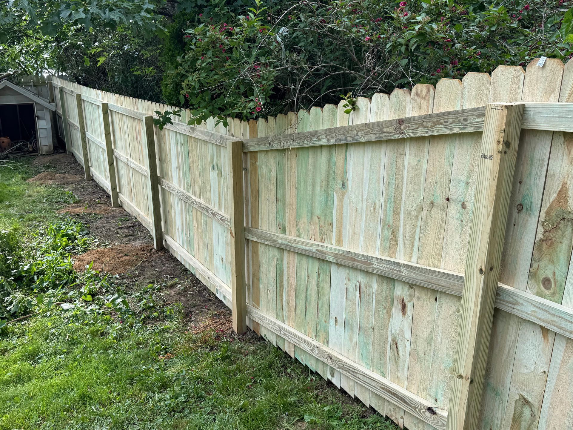 Wooden fence in a grassy yard, separating the property.