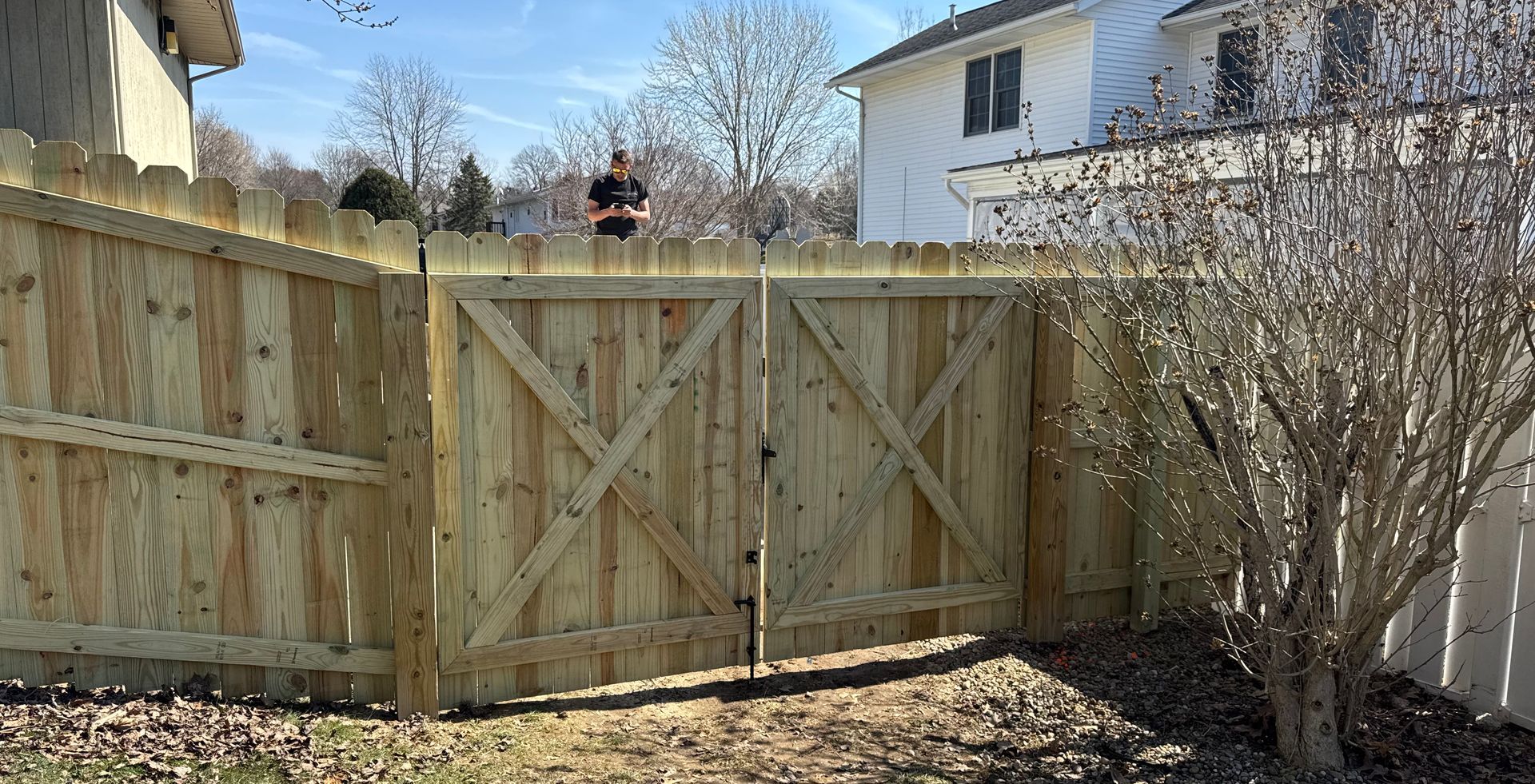 Wooden fence with gate and an obscured person.