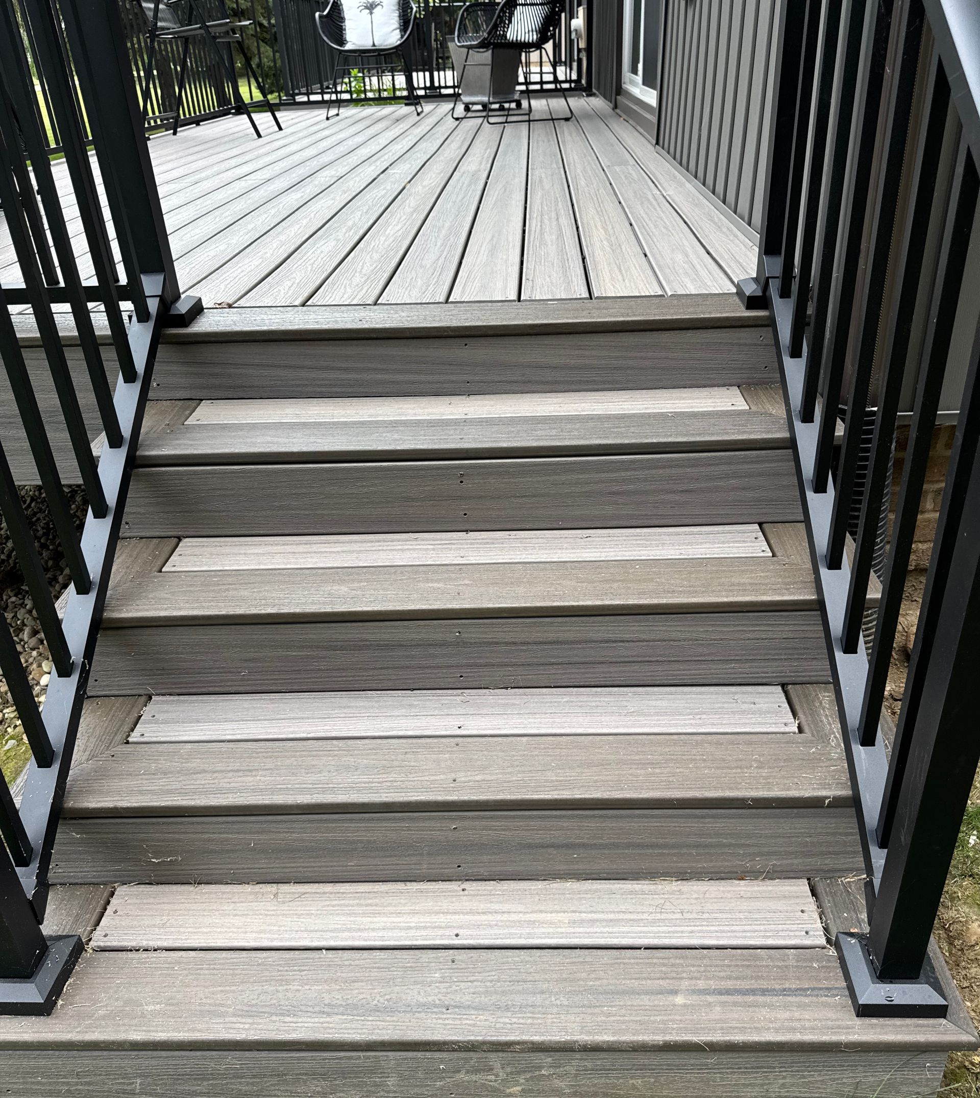 Wooden deck stairs with black railing leading to a composite deck.