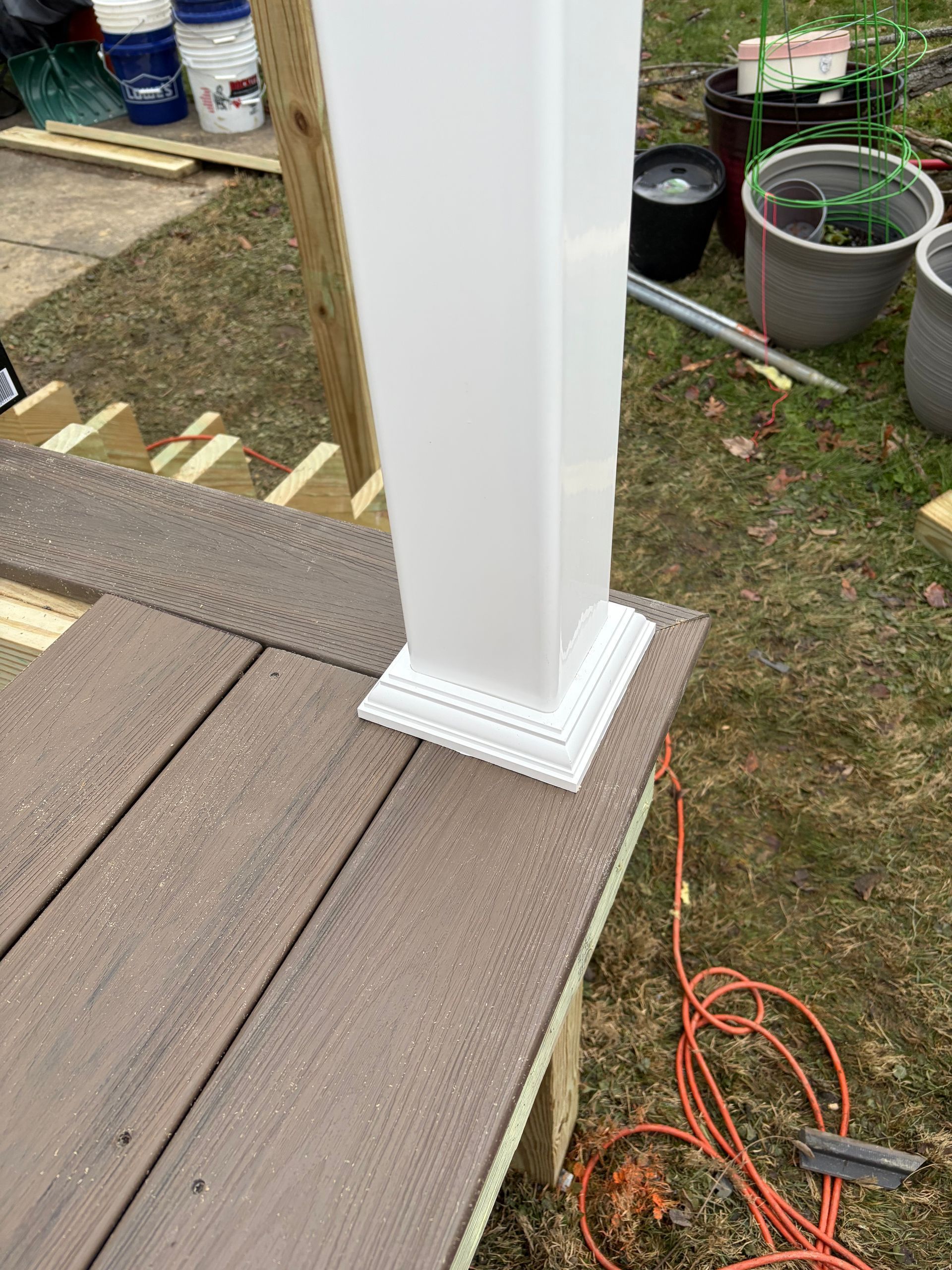White square post on a brown composite deck with a decorative base