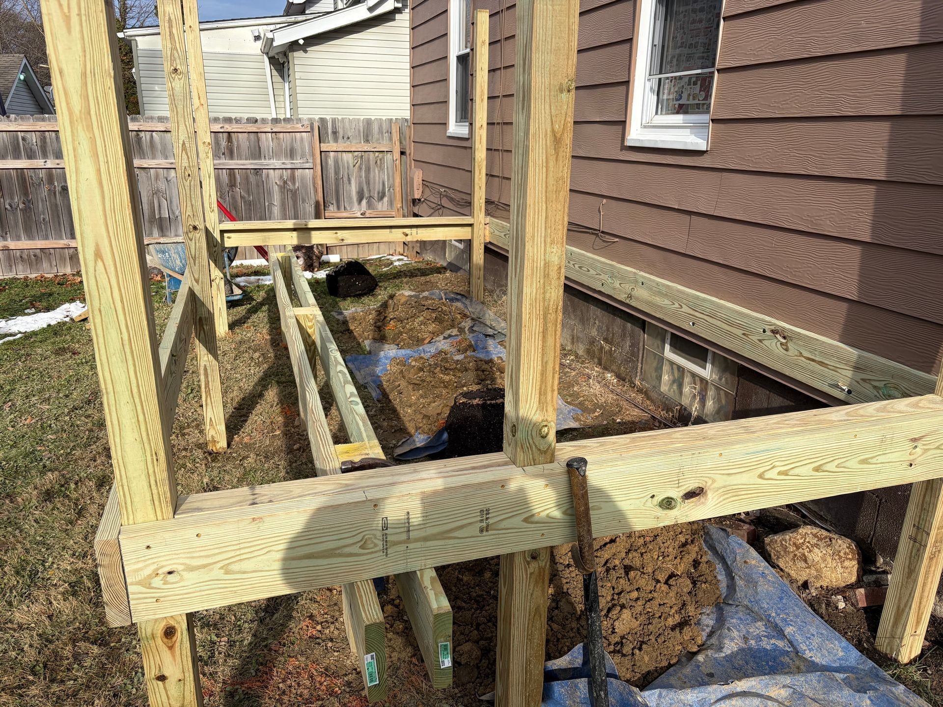 Wooden deck frame being built next to a brown house