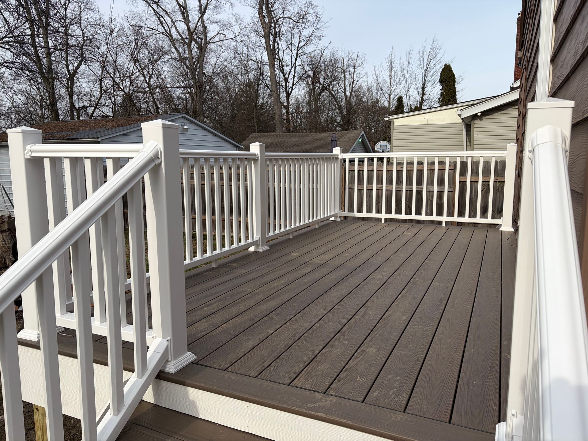 Brown deck with white railing in a residential backyard