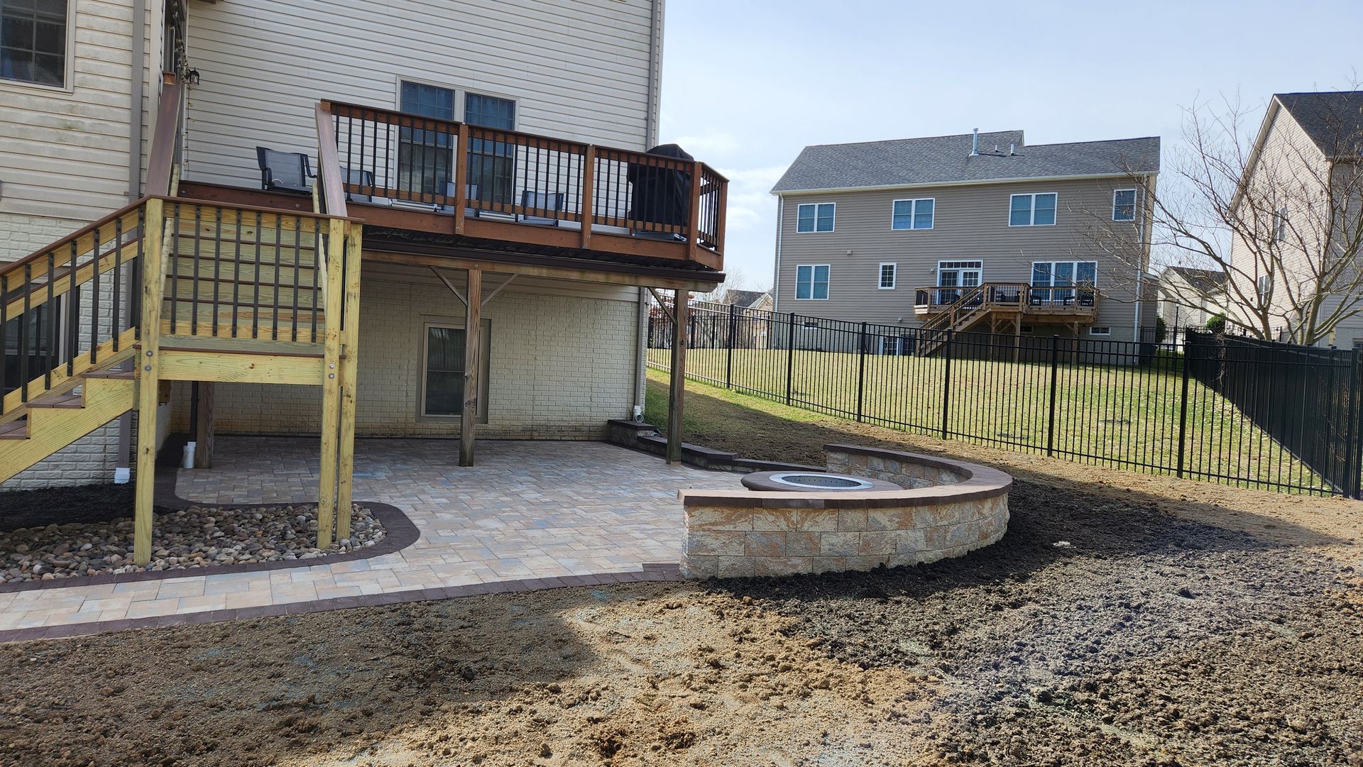 a wooden deck with stairs leading up to it is in the backyard of a house .
