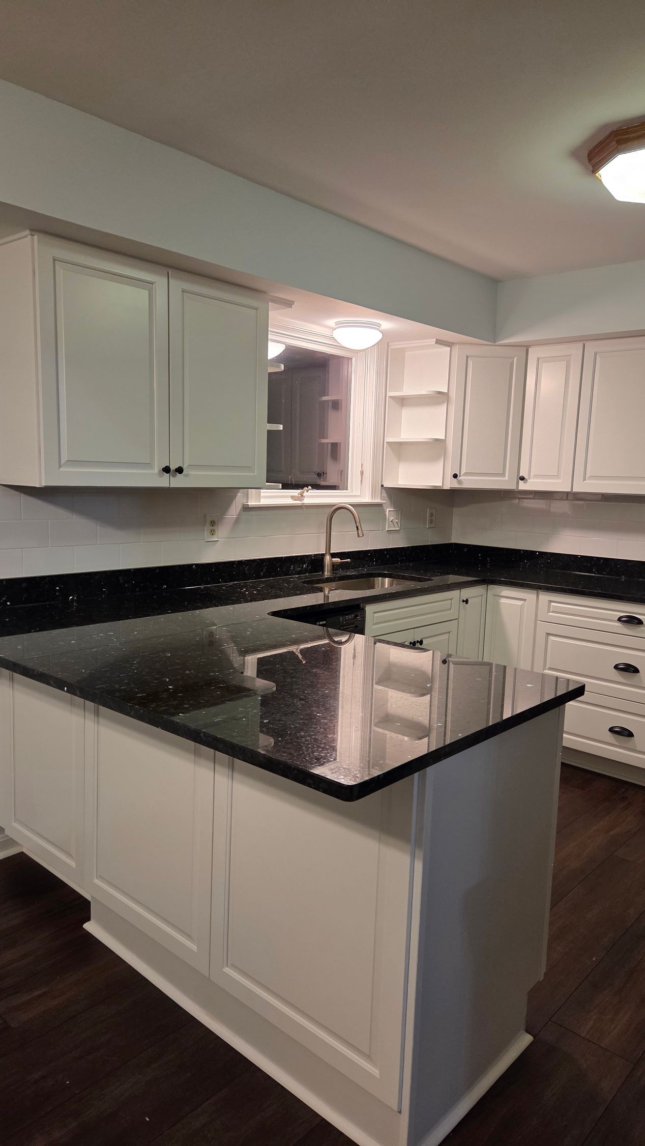 White kitchen with black countertops, island, and cabinets.
