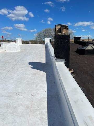 A white roof with a black chimney on top of it.