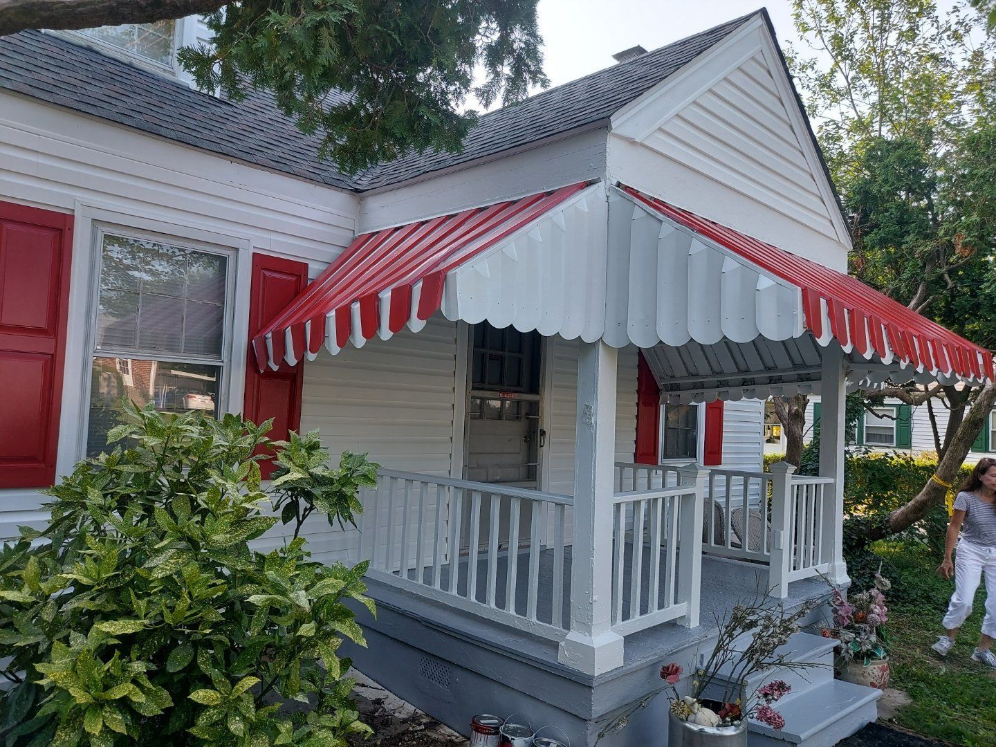 a white house with a red awning on the porch
