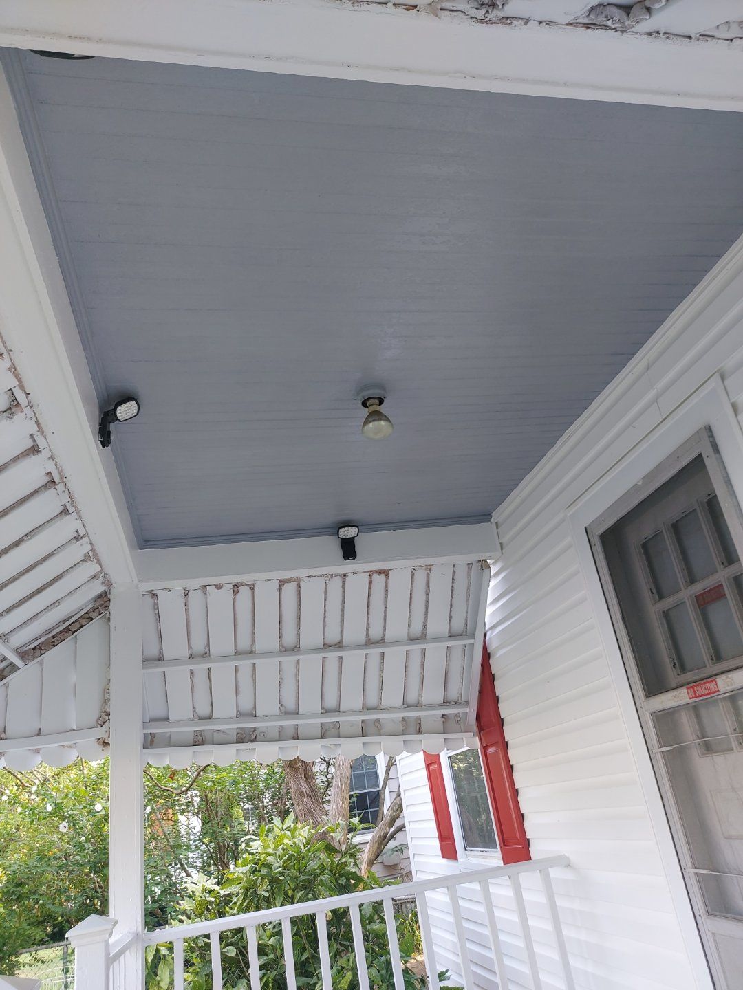 a white house with a porch and a blue ceiling