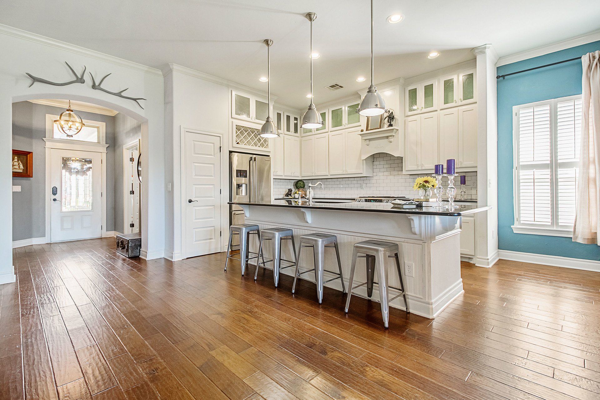 a kitchen with hardwood floors, white cabinets, stainless steel appliances, and a large island