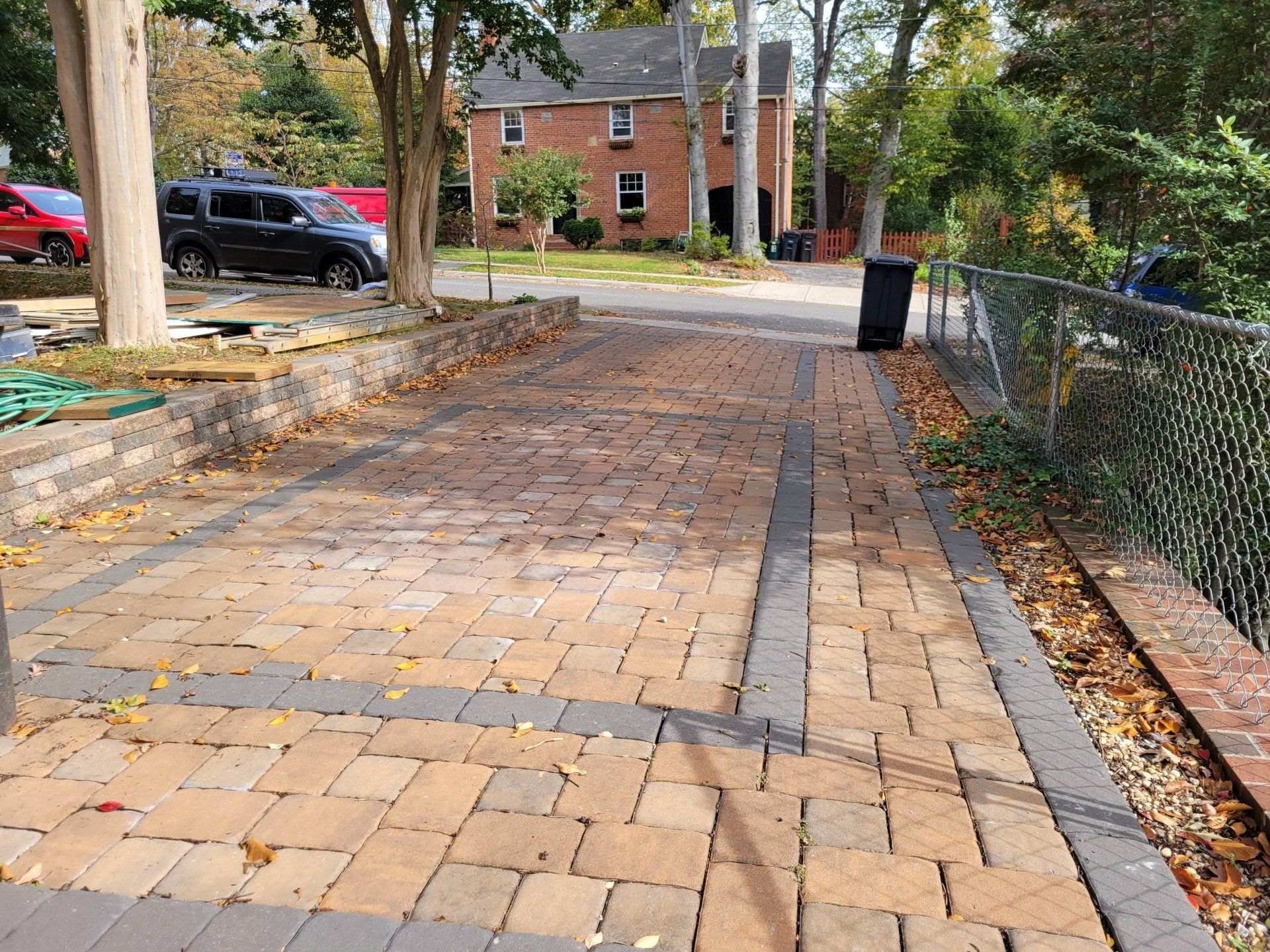 a brick walkway with a trash can on the side of it