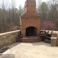 a brick fireplace is sitting on top of a patio next to a stone wall