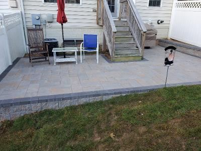 a patio with chairs, a table, and an umbrella in front of a house