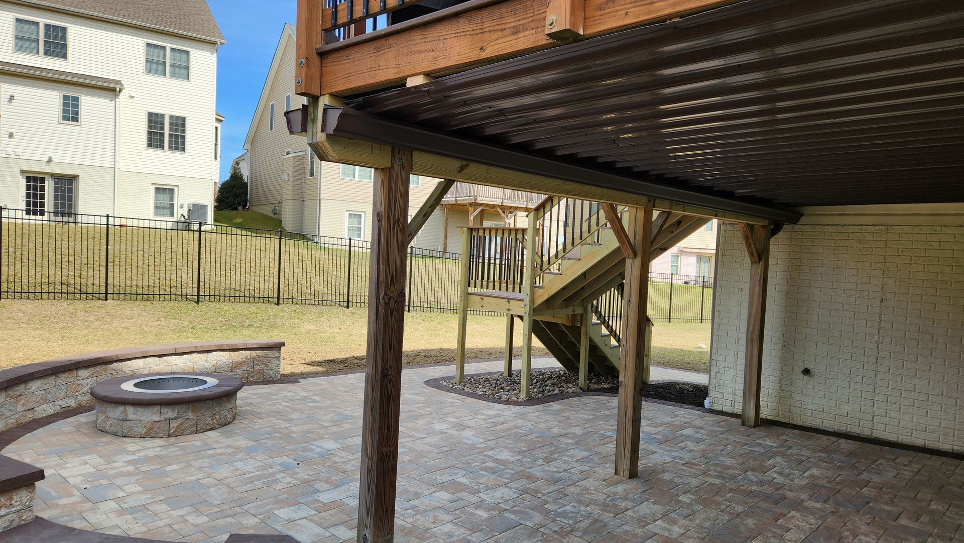 a wooden deck with a fire pit and stairs underneath it