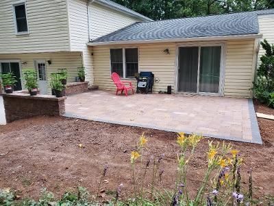 a backyard with a patio and chairs in front of a house