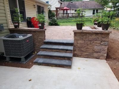 a patio with stairs leading up to a house and a brick wall