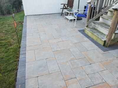 a patio with chairs, a table, and stairs next to a house