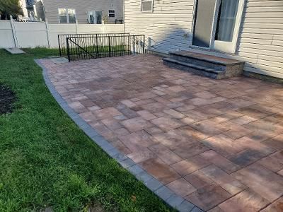 a brick patio with stairs and a railing in front of a house