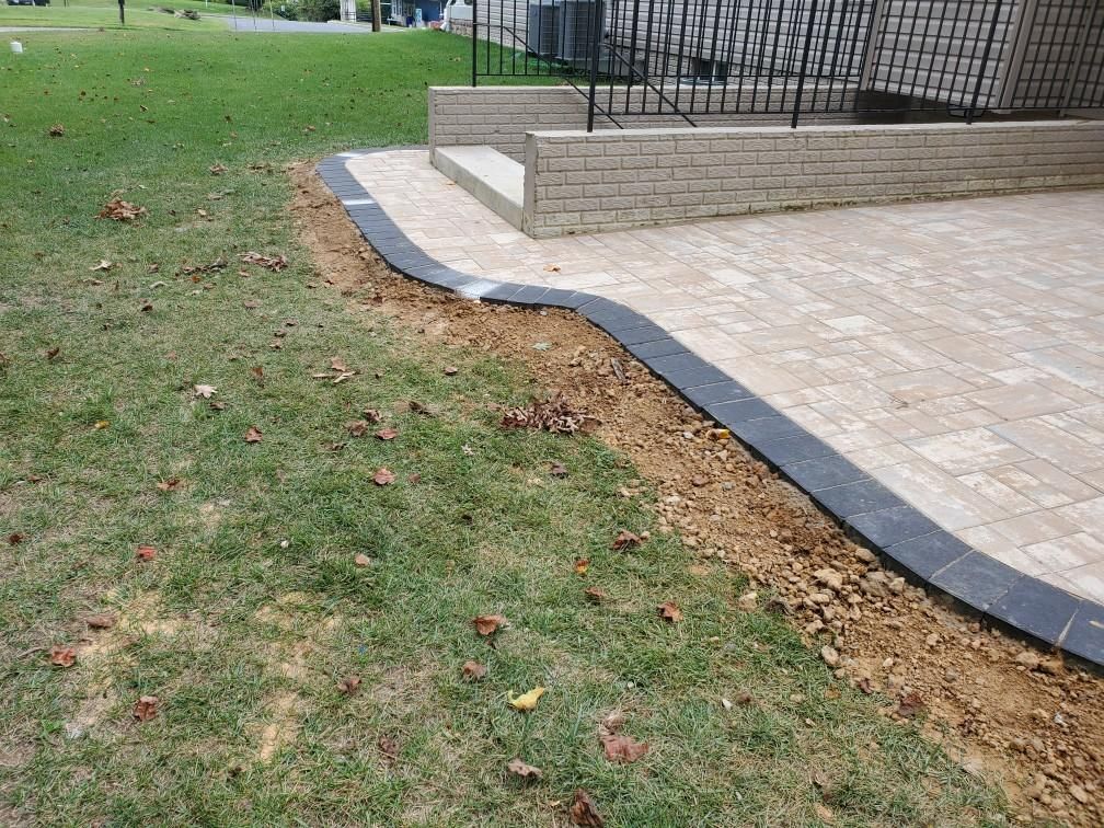 a brick walkway is being built in the grass next to a house