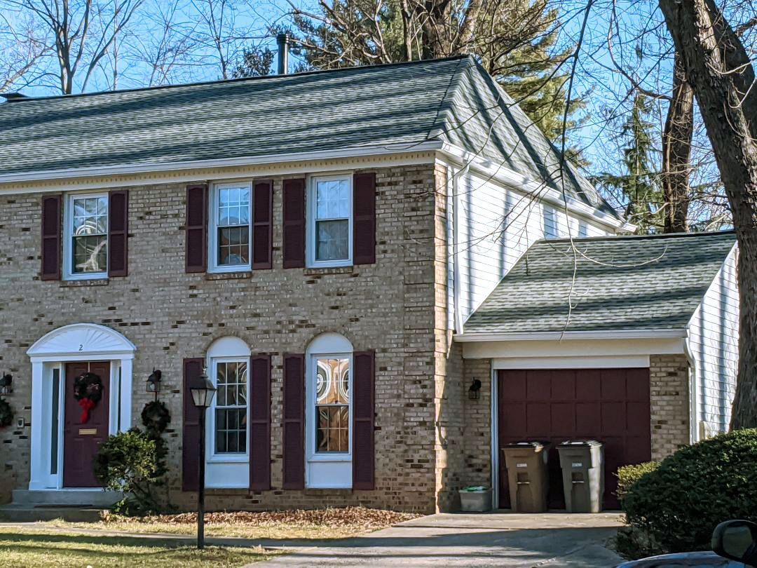 a brick house with a green roof and a red garage door