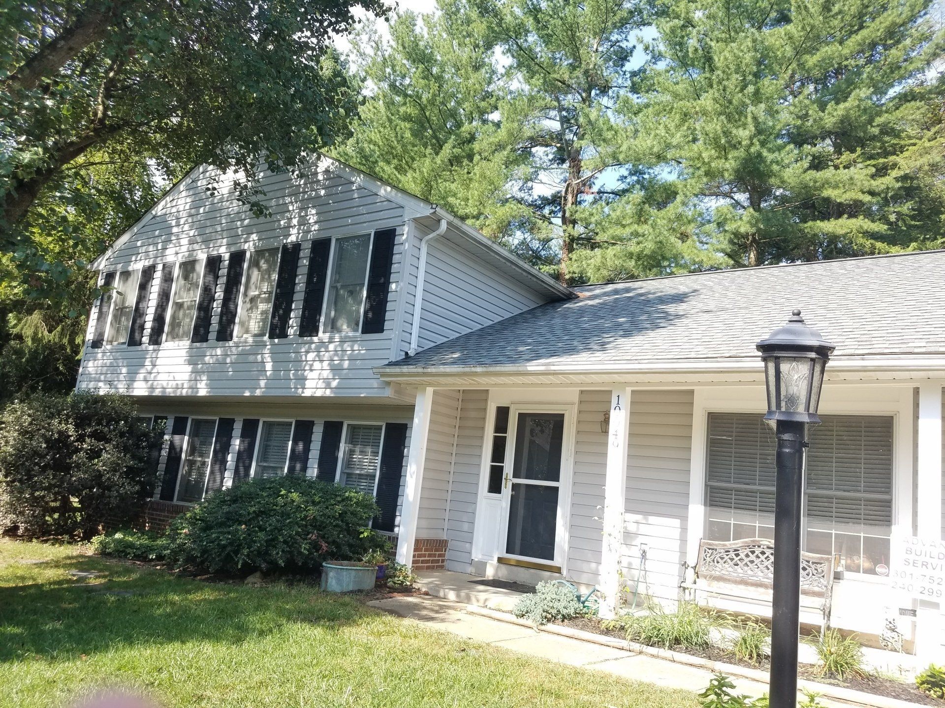 a white house with black shutters and a lamp post in front of it