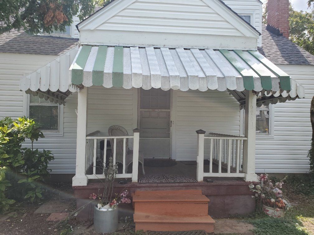 a white house with a green and white awning on the porch
