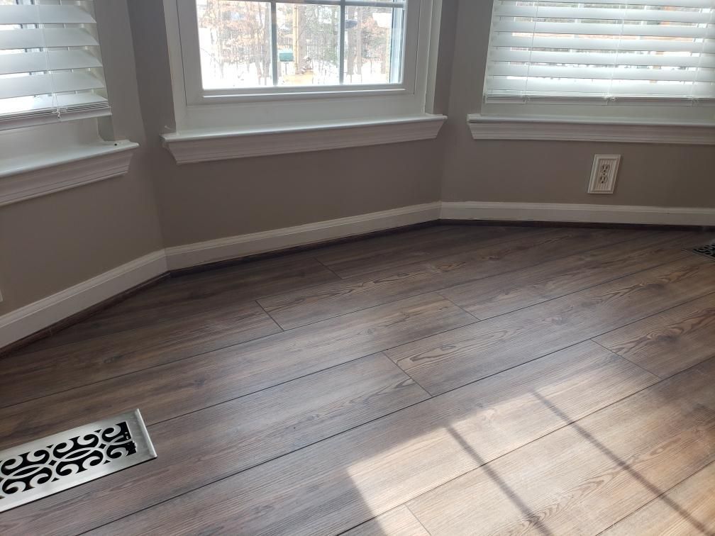A room with a wooden floor and a window with blinds