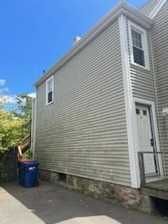 A small house with a blue trash can in front of it.