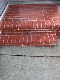 A red brick porch with steps leading up to it.