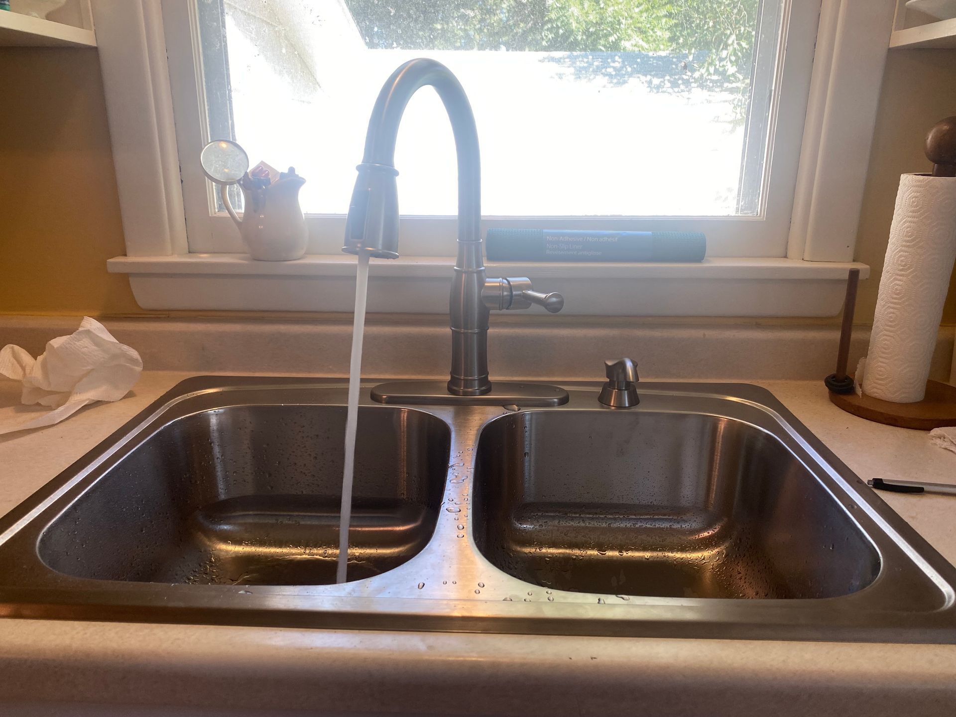 A kitchen sink with water running from the faucet
