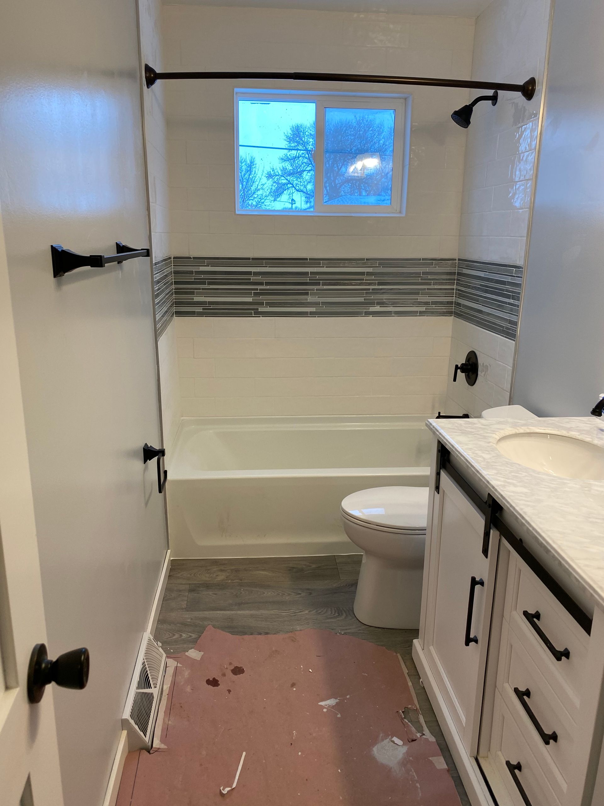 A bathroom with a toilet, sink, bathtub, and window.