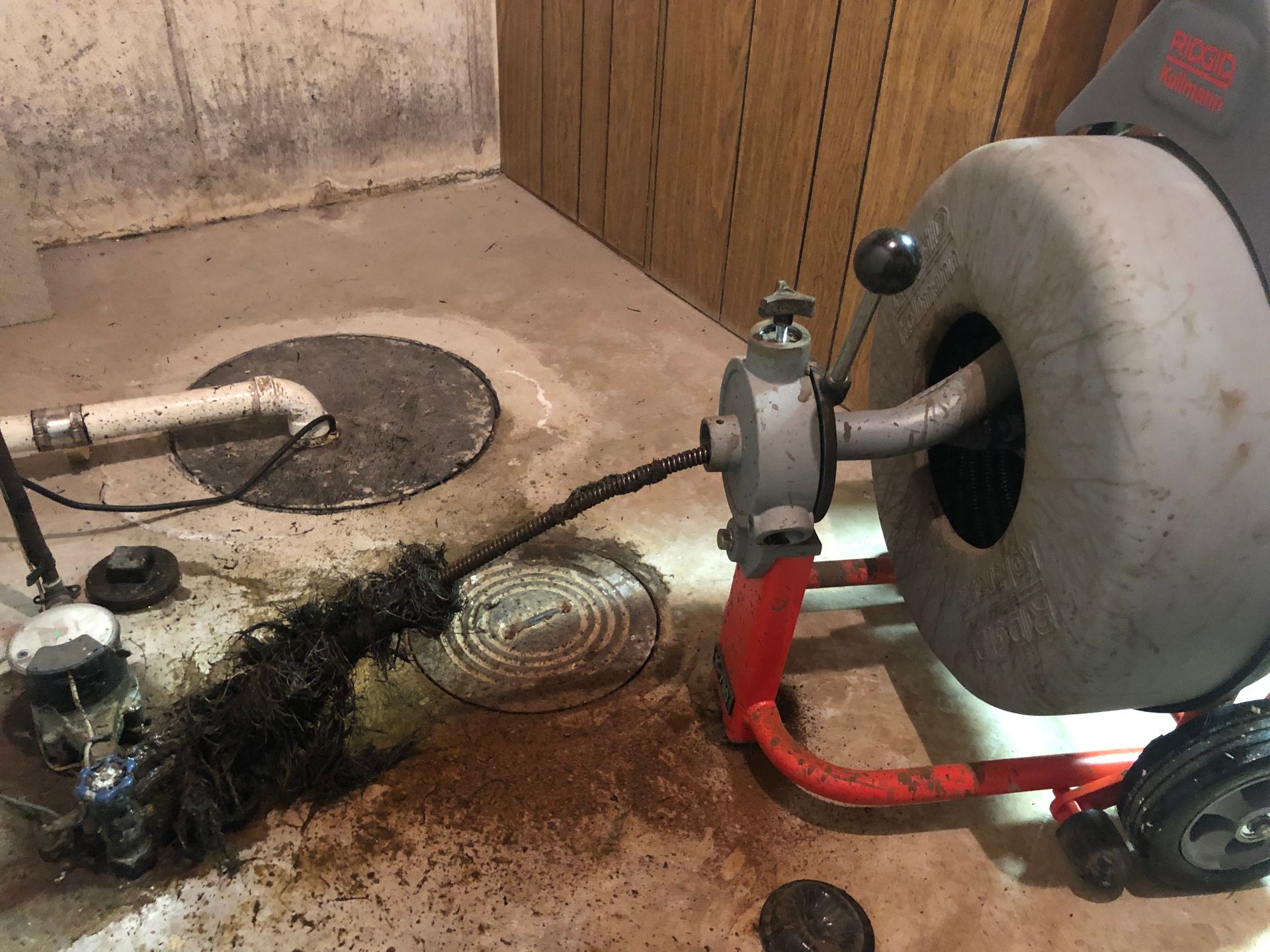 A drain cleaner is being used to clean a drain in a basement.