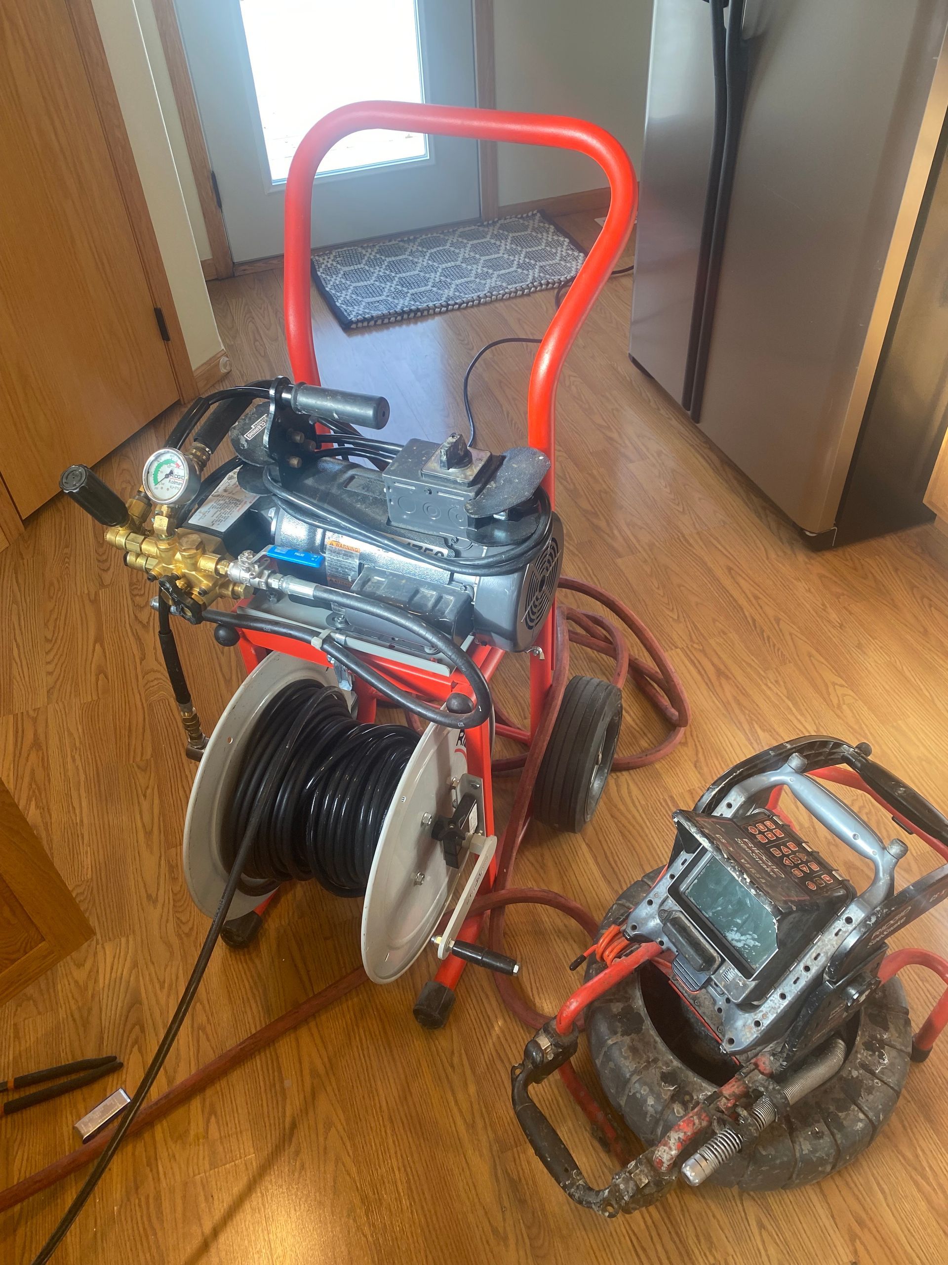 A machine is sitting on a wooden floor next to a drain camera.