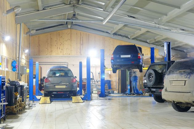 Auto repair shop with cars on lifts and mechanics working in a bright garage