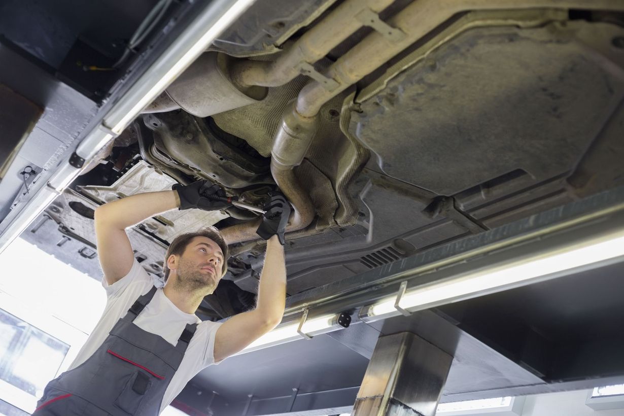 Mechanic inspecting the underside of a car on a lift in an auto repair shop