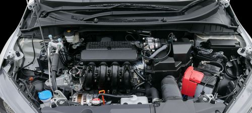 Open car engine bay with visible battery, hoses, and components under the hood